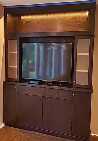 Midcentury entertainment center in dark stain with concealed glass and lighted shelves.