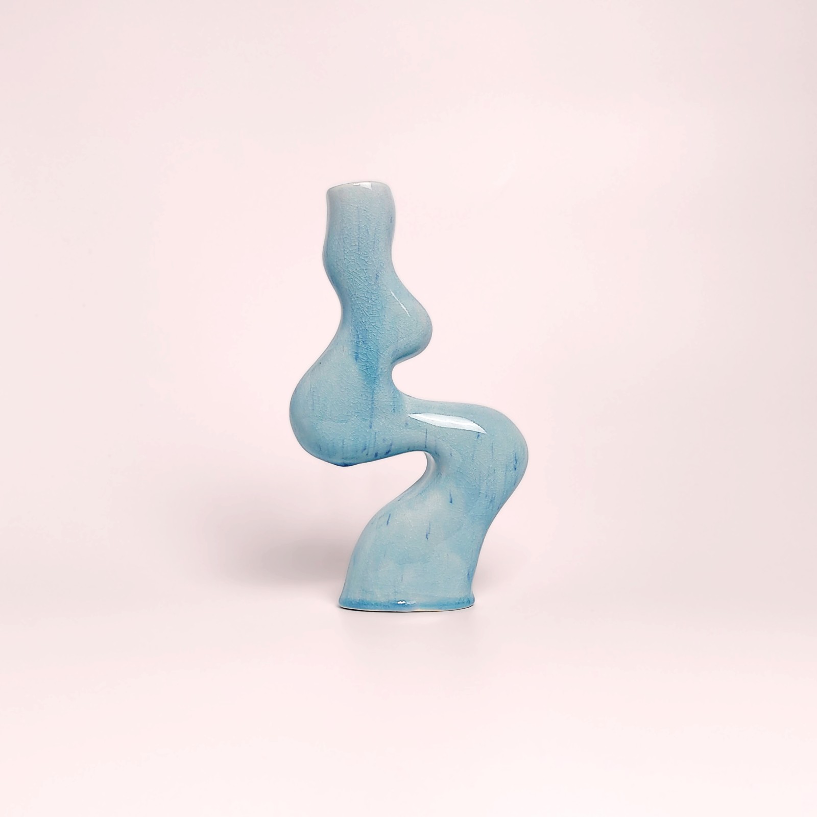Unique handmade sculptural ceramic candle holder featuring a flowing wavy form and glossy blue glaze, designed for a single tall candle