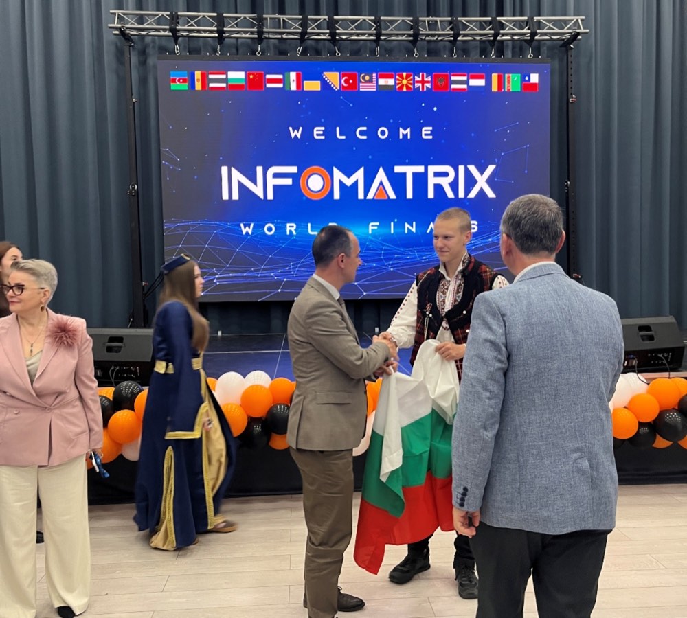 Участник на Robocode в българска народна носия с националния флаг на финала Infomatrix 2026