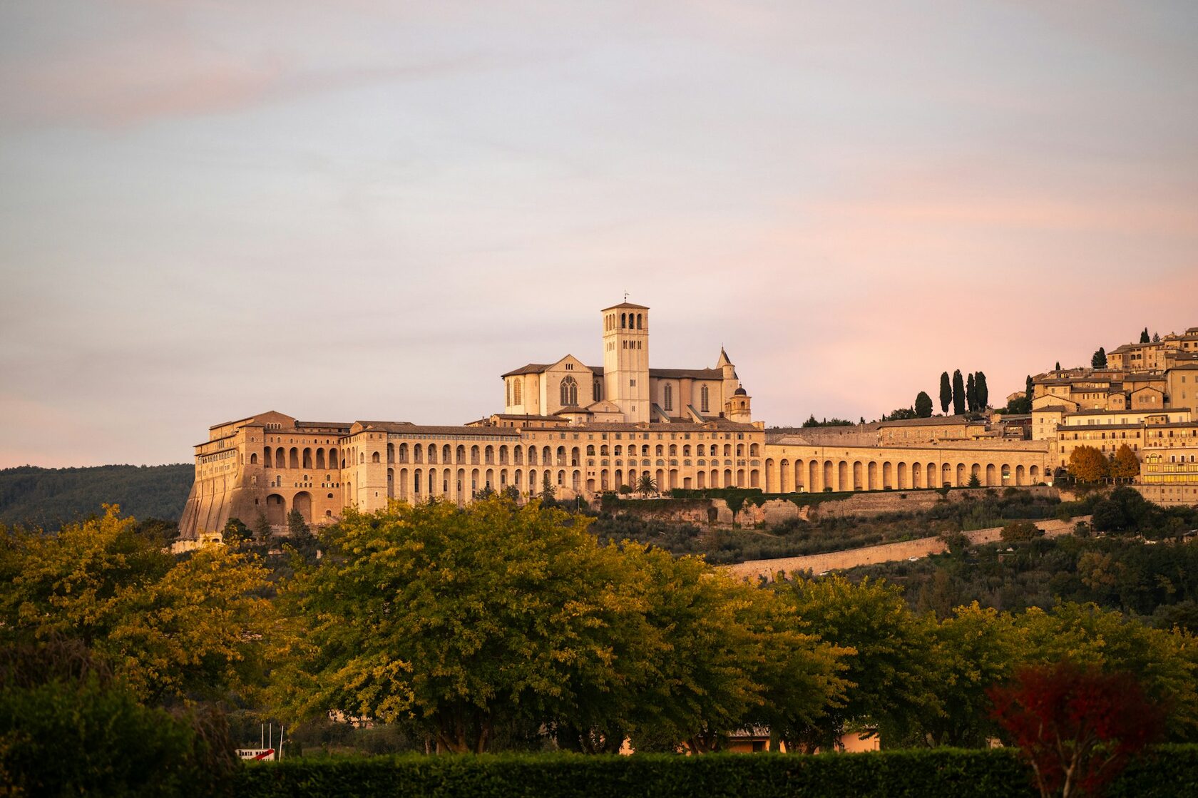 The Basilica of St. Francis in Assisi glowing above the Umbrian plain at dusk