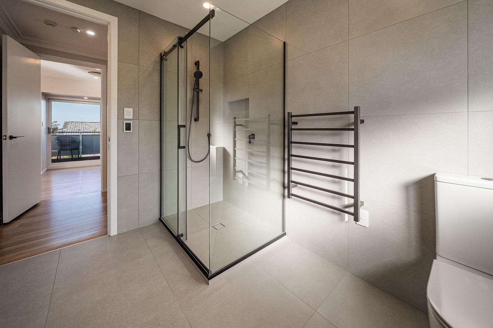 Walk-in shower with black framing and a heated towel rail in the Glenfield bathroom