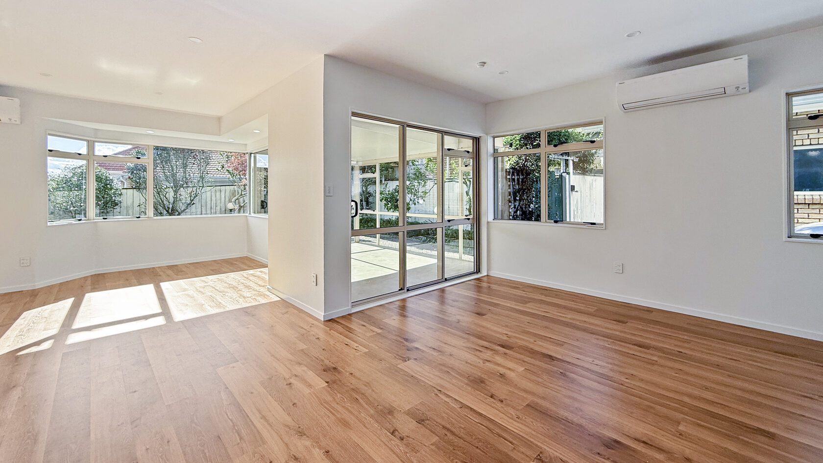 Open-plan living and dining area with renovated timber flooring in St Heliers, Eastern Bays.
