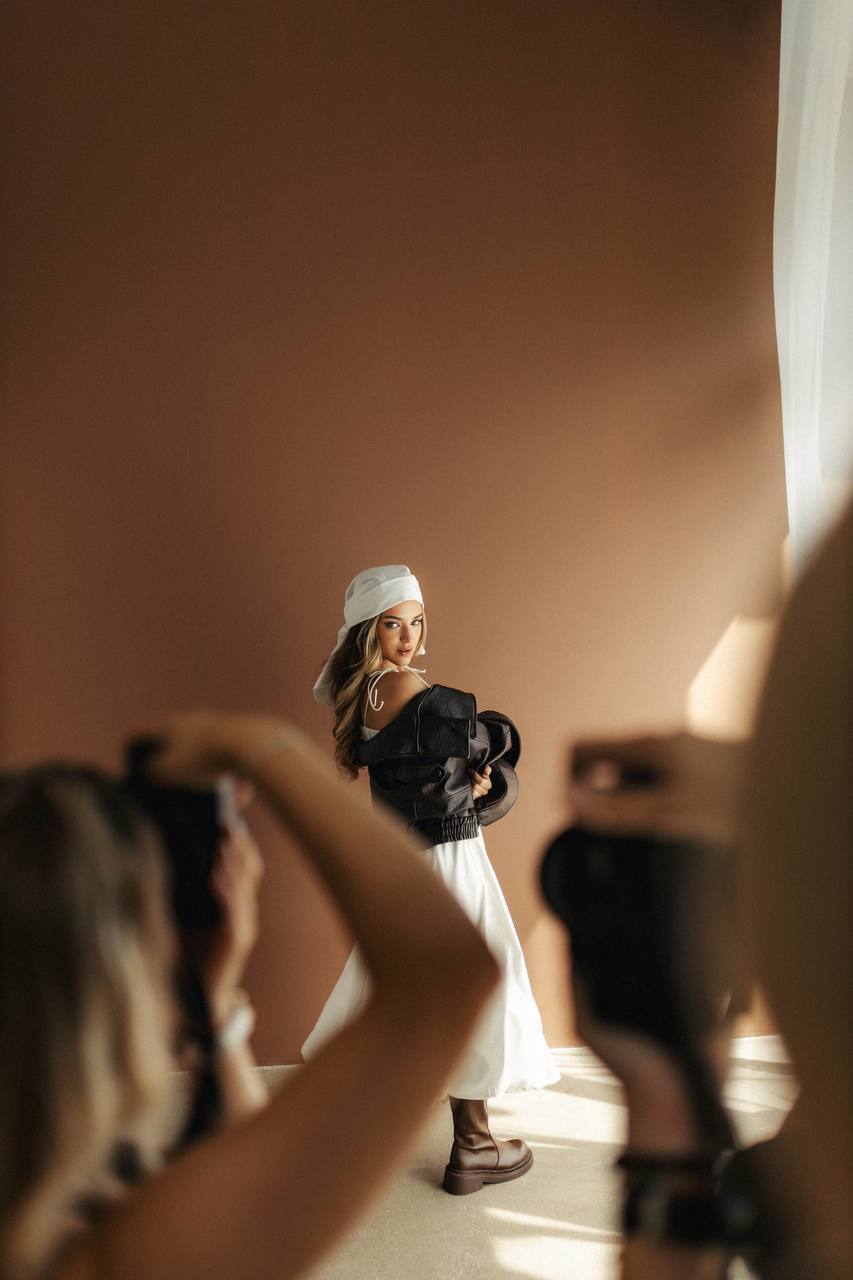 Backstage warsztatu portfoliowego KARIROOM: dwoje fotografów fotografuje modelkę przy brązowej ścianie