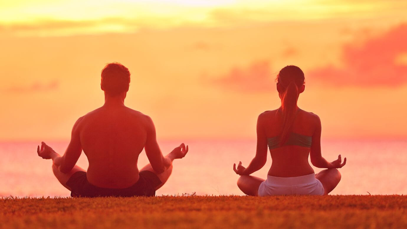 Man and woman sitting together gazing at a serene sea sunset while deep in thought