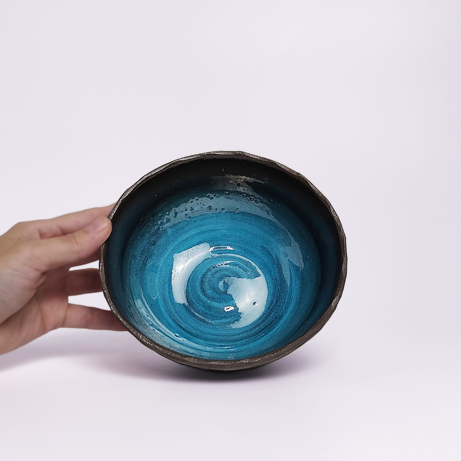 unique handmade ceramic bowl with dark clay exterior and vibrant deep blue glaze, artistic decorative tableware