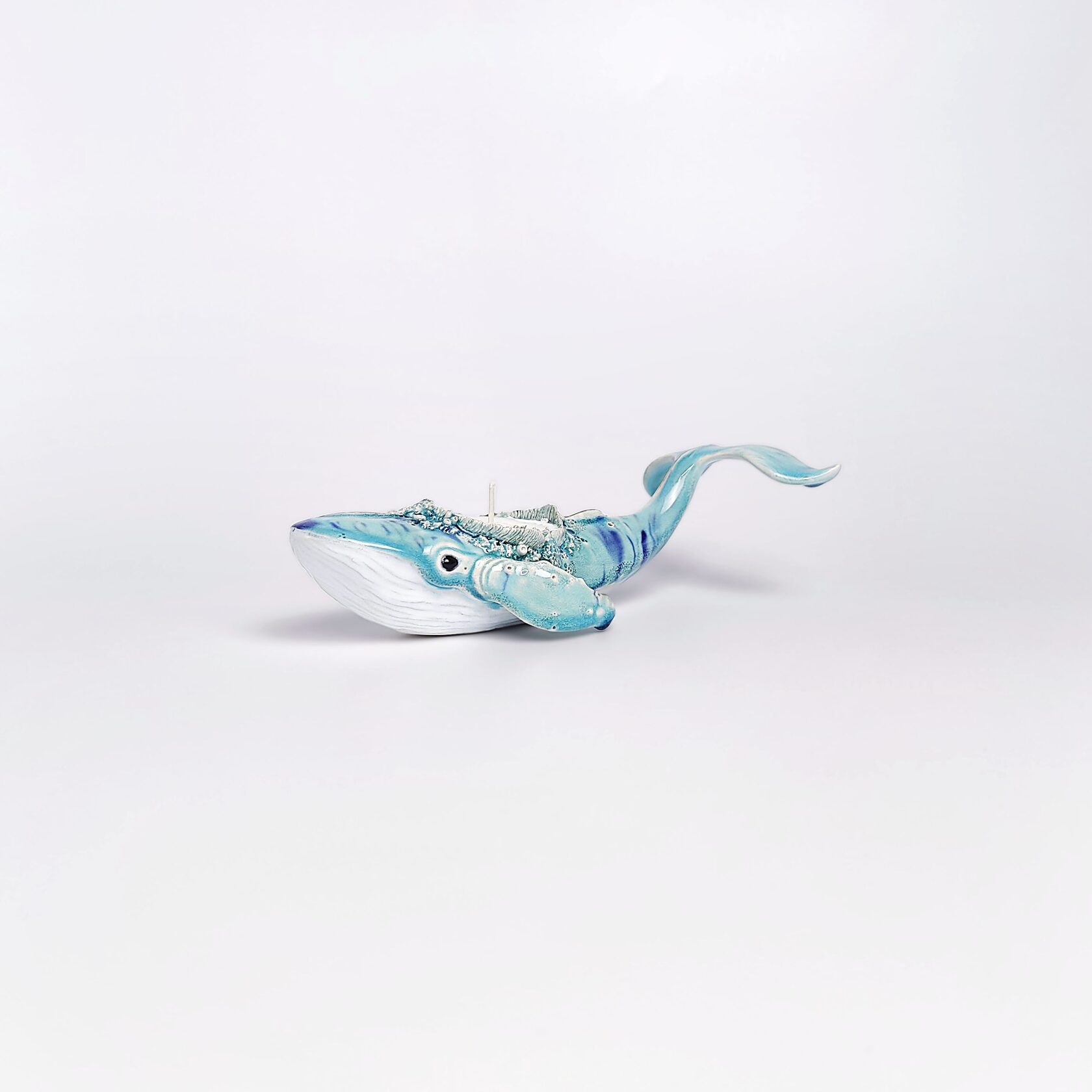 Unique handmade ceramic whale candle holder with ocean-blue glaze, detailed sculptural texture, and a built-in candle