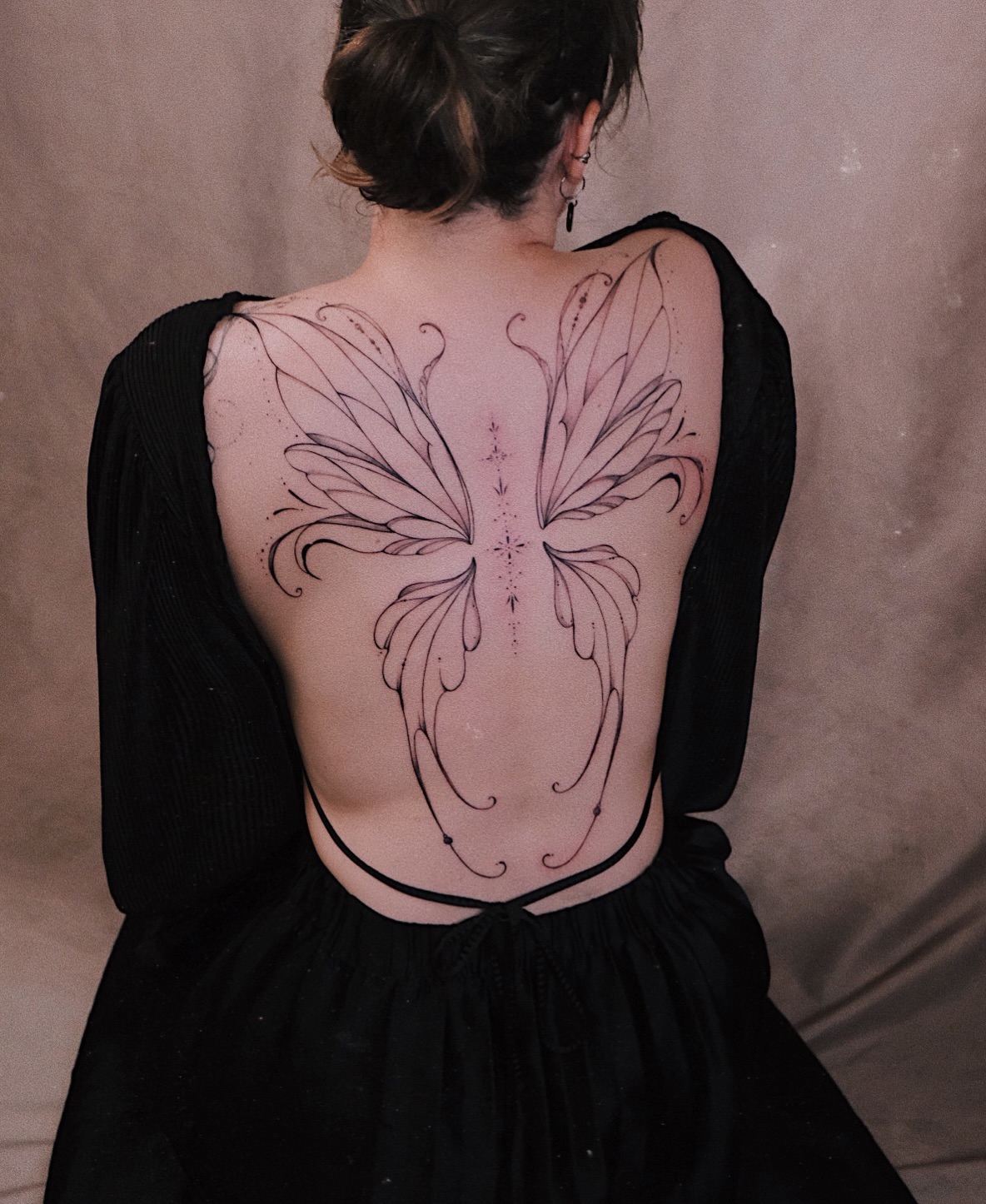 Large symmetrical fine line back tattoo with wing-like shapes and stars by Cathy