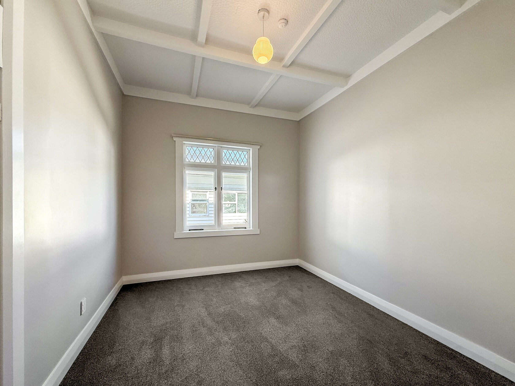 Carpeted room with a central timber-framed window and ceiling light