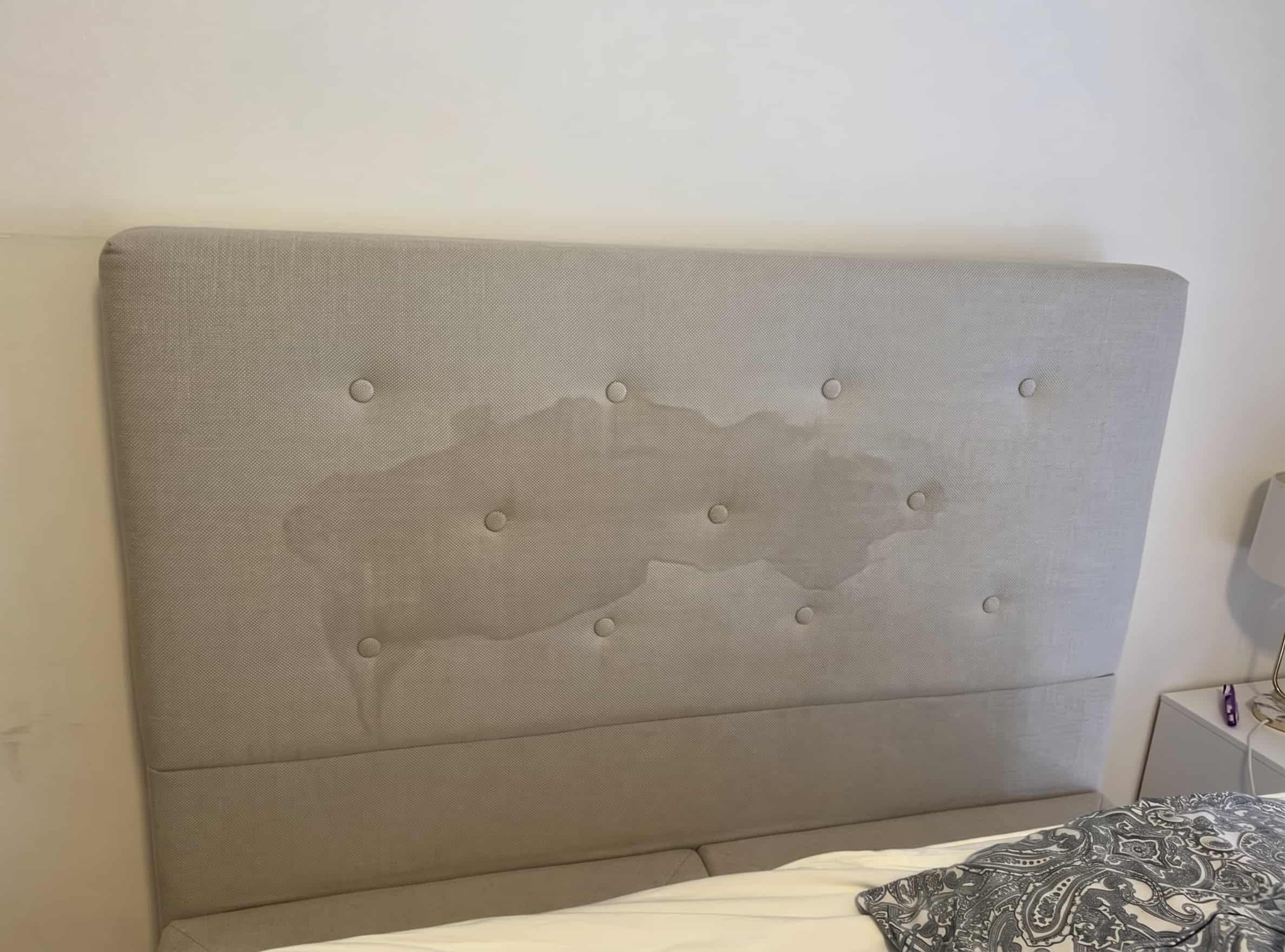 Gepolstertes Bett-Kopfteil mit Gebrauchsspuren, dunklen Stellen und Hautfettr&uuml;ckst&auml;nden vor der Reinigung. Kopfteile werden beim Reinigen meist vergessen, obwohl sie t&auml;glich Kontakt mit Haut und Haaren haben.