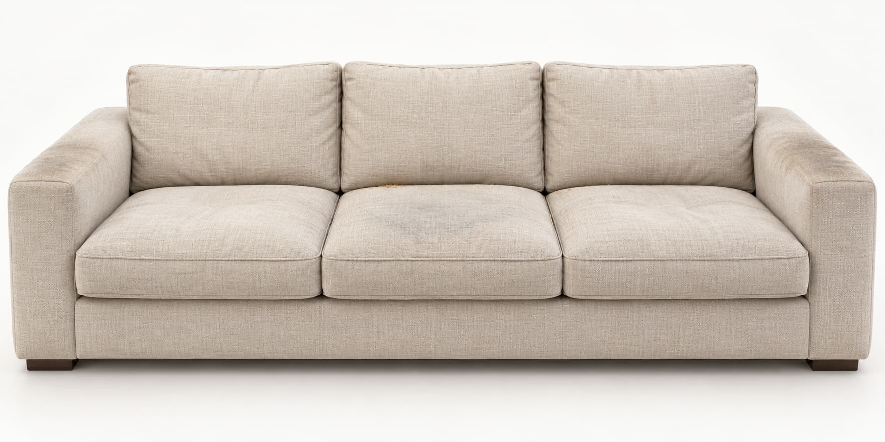 Symbolbild: helles Dreisitzer-Stoffsofa mit speckigen Armlehnen, Grauschleier auf dem mittleren Sitzkissen und Kr&uuml;meln in der Ritze. Shikardos Reinigung aus Frankfurt zeigt, welche Stellen ein Topfdeckel mit Tuch erreicht und welche nicht.