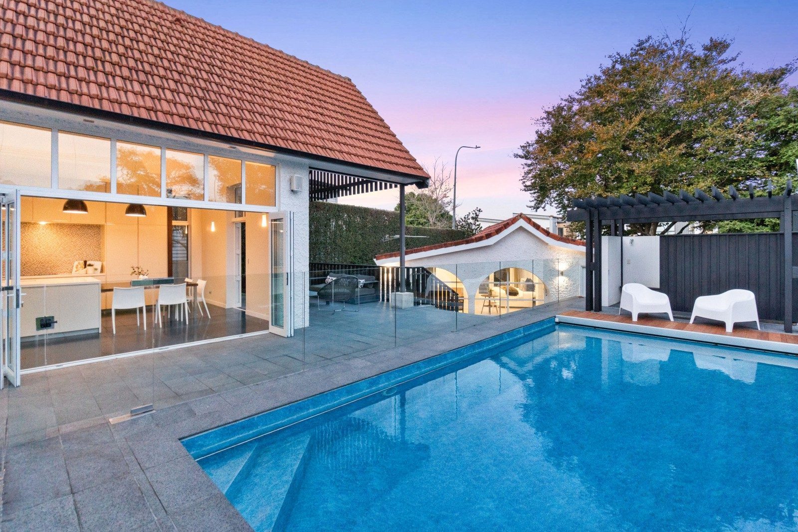 Owens Road Epsom home at dusk, with open kitchen doors beside the swimming pool
