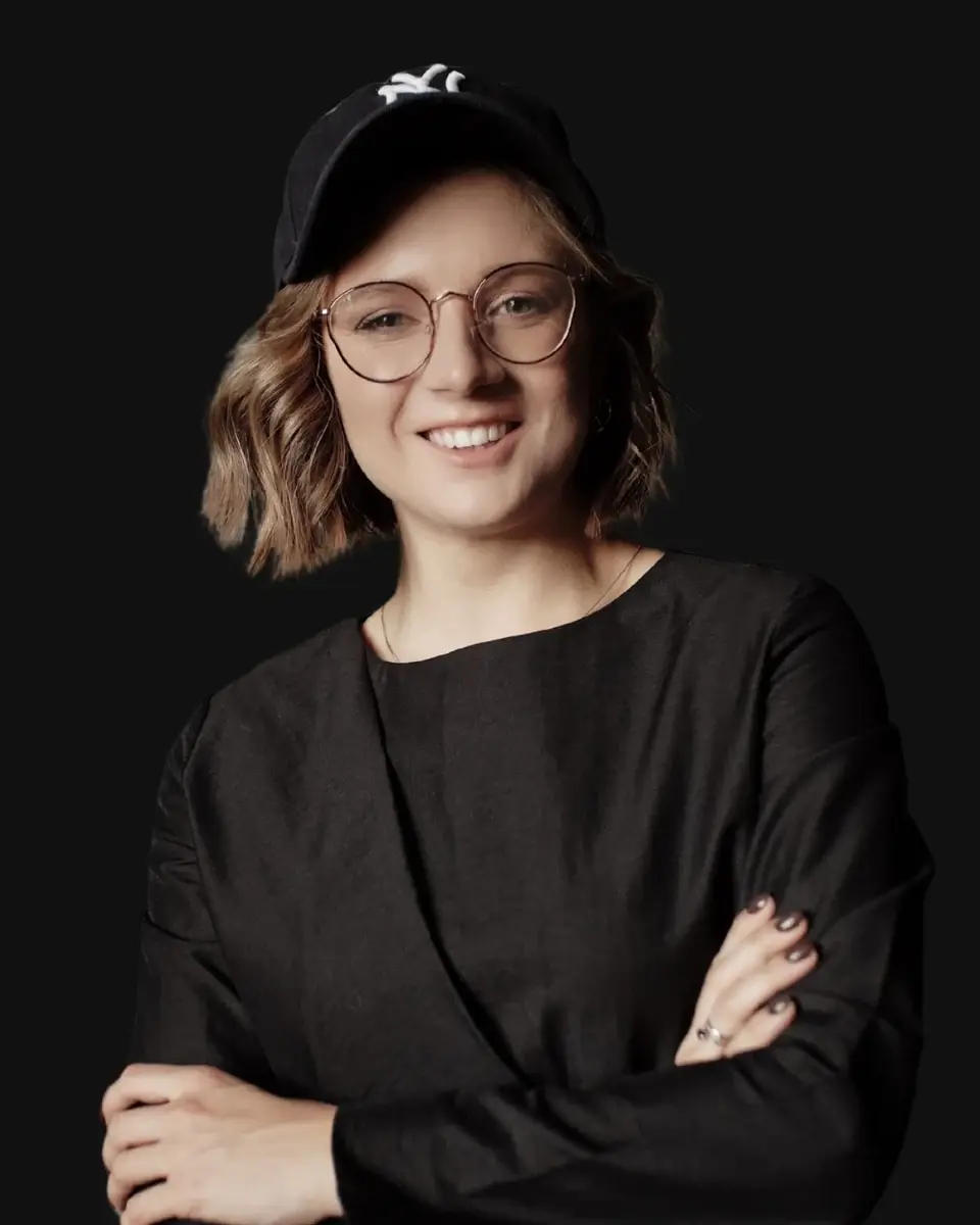 Marina Baslina smiling, wearing glasses and a black cap