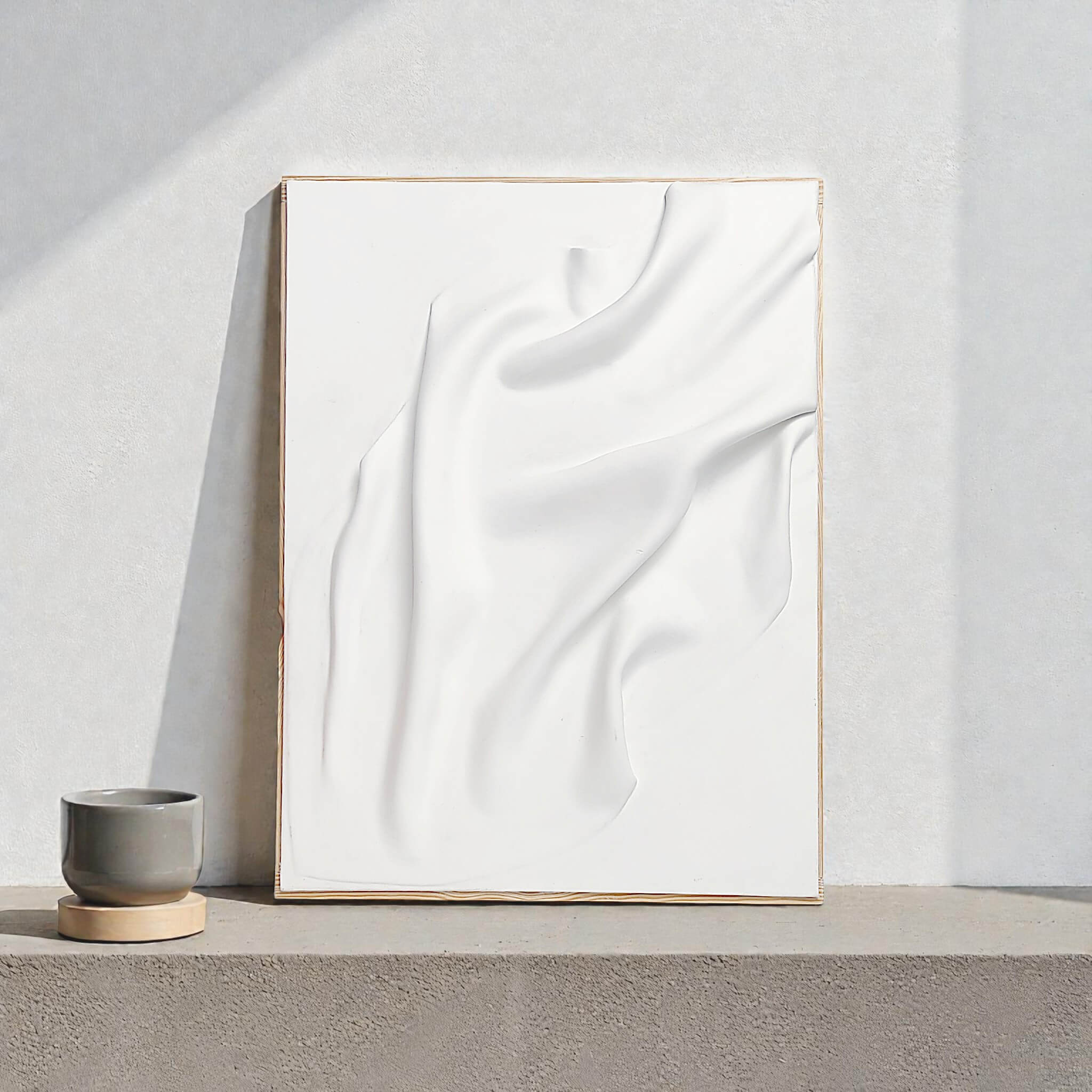 White handmade wall art with sculptural texture resembling soft fabric folds. Minimalist ceramic artwork for contemporary interior décor.
