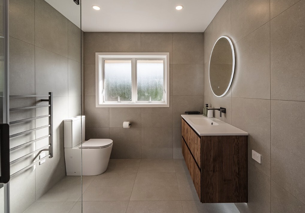 After: renovated Glenfield bathroom with grey tiles, wall-hung vanity and LED mirror