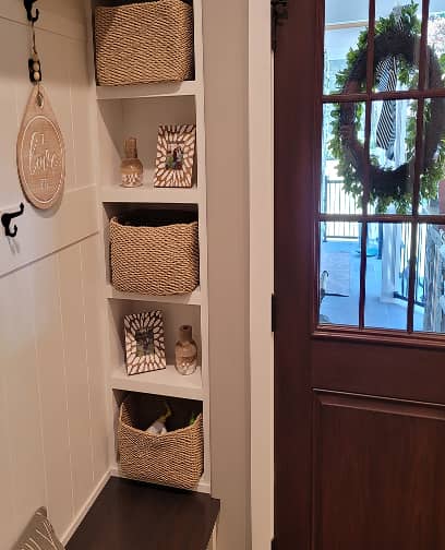 Mudroom shelves and built-in dark stained bench furnished with baskets and hooks 