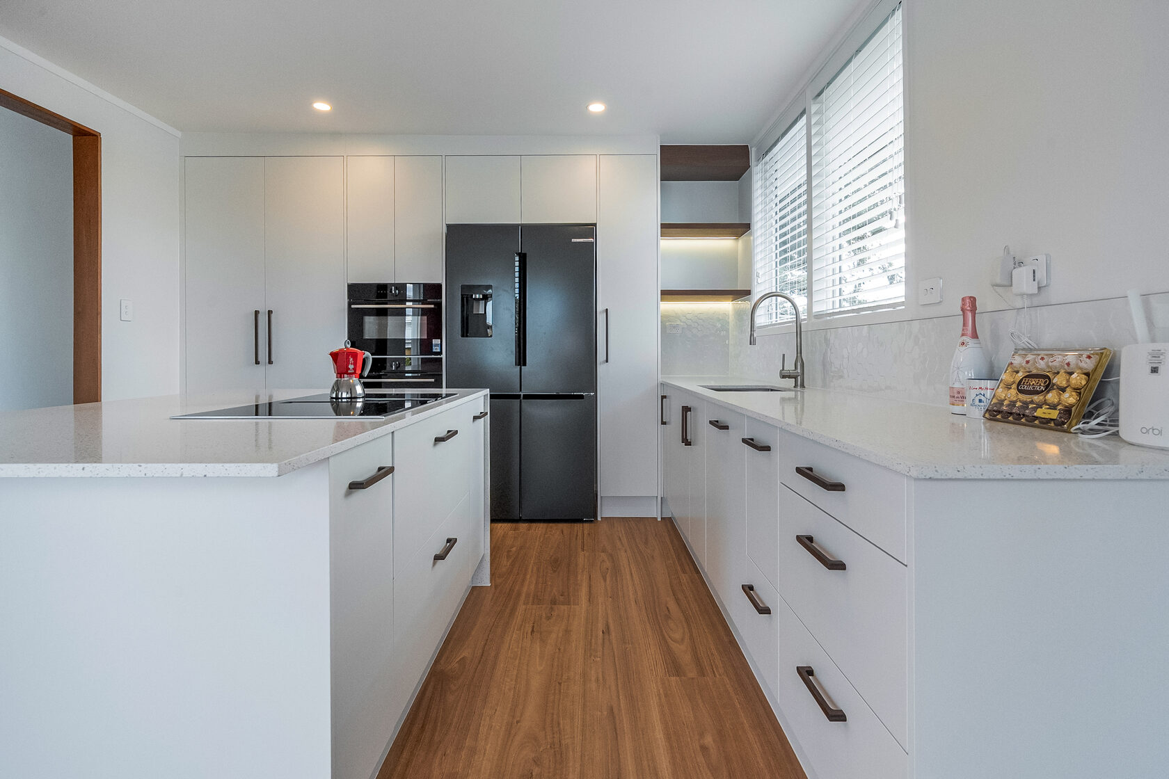 Completed Hillcrest kitchen with white cabinetry, a central island, built-in appliances and timber flooring