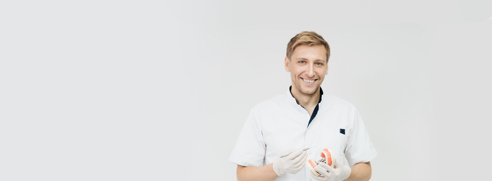 Zobārsts tur zobu modeli ar instrumentu