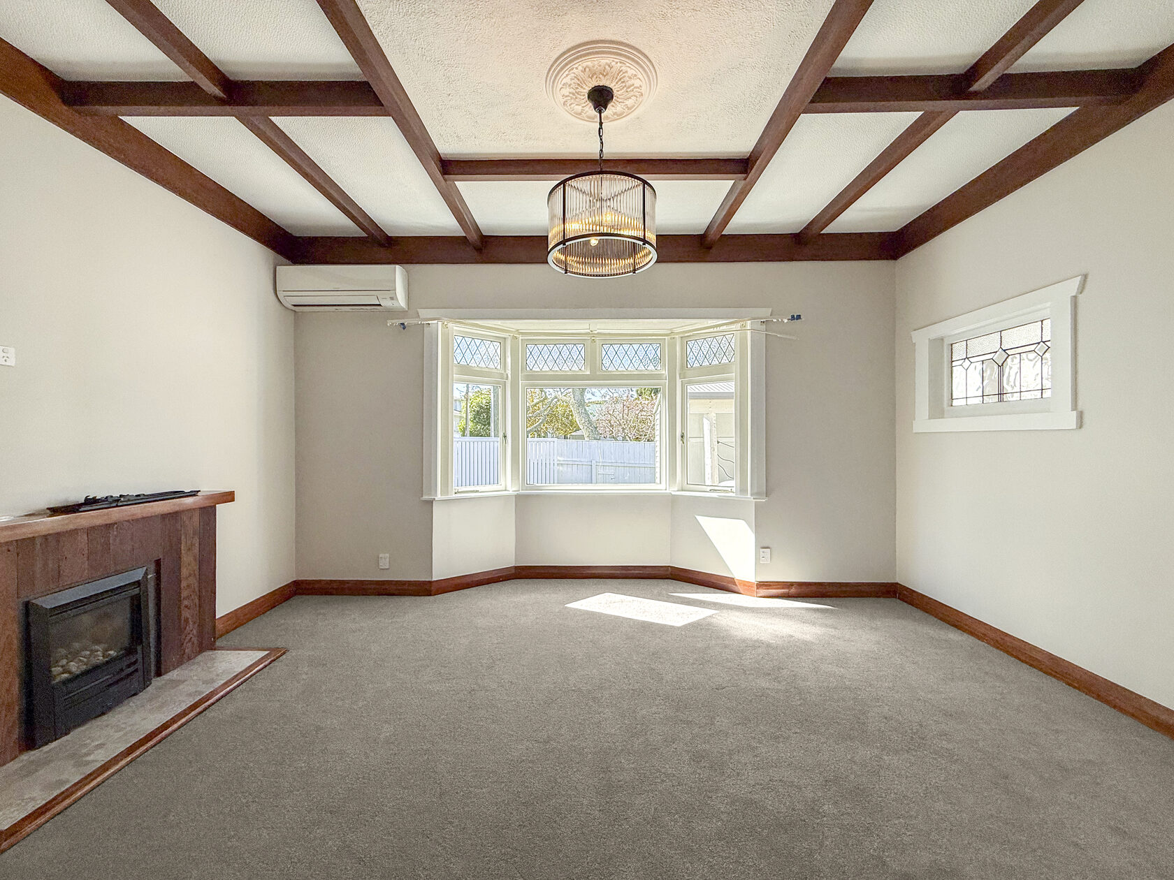 Bungalow living room with timber ceiling beams, fireplace and bay window
