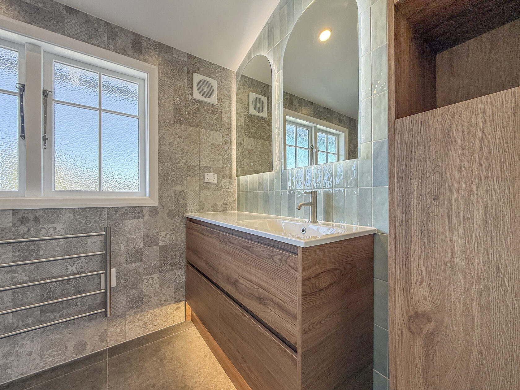 Timber bathroom vanity with under-cabinet lighting and mirrored wall