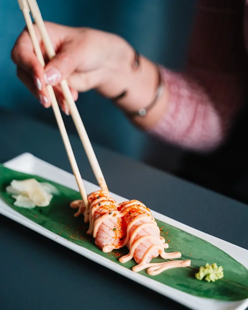 foto di una mano che prende i nigiri con le bacchette