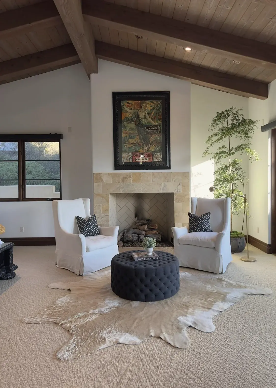 A living room with a fireplace, planted with tall indoor trees