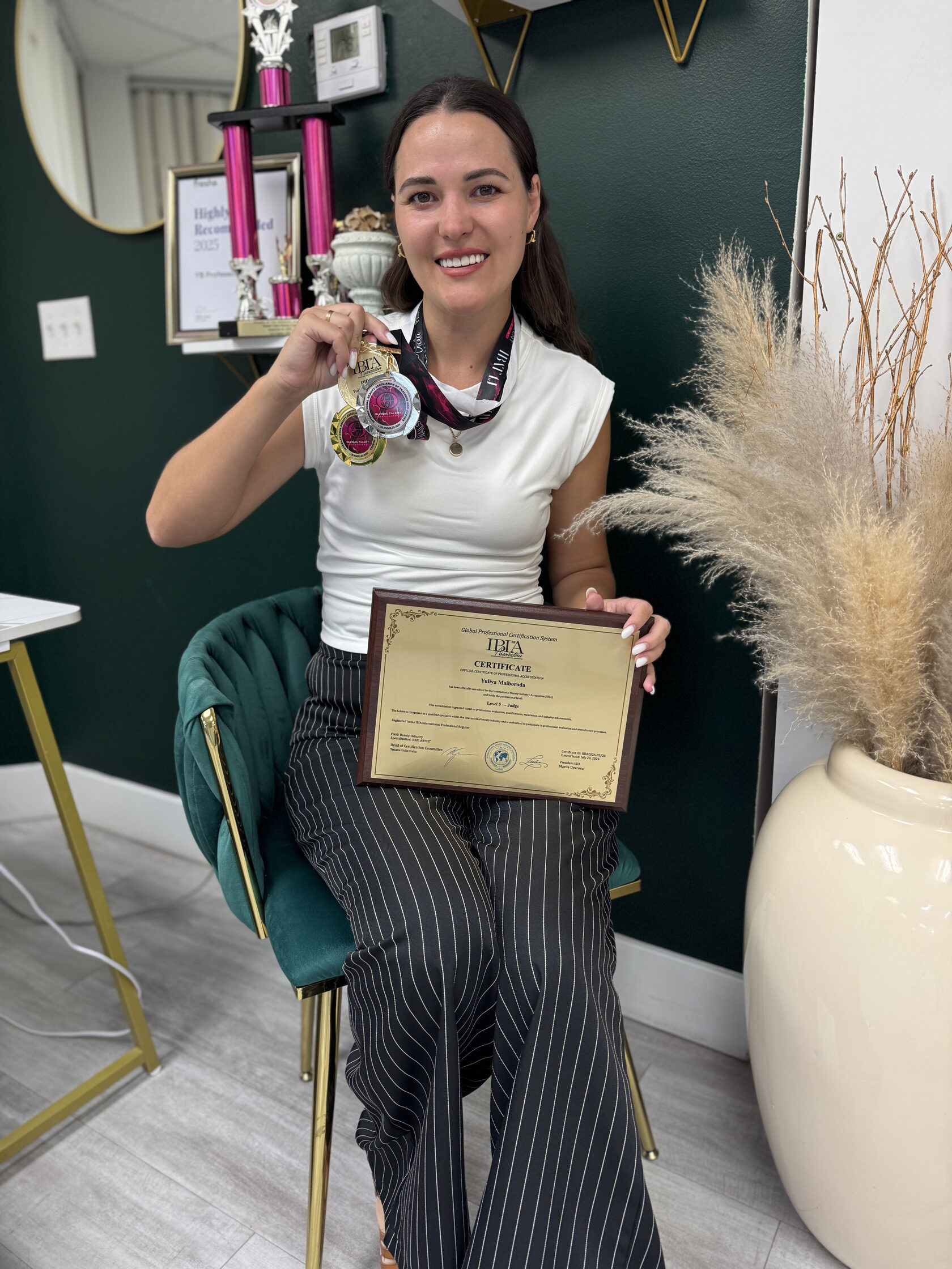 Yuliya with her professional nail industry judging certificate and awards