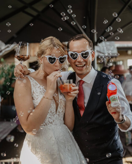 Playful wedding celebration with heart sunglasses and bubbles — candid mountain wedding moments in Austria