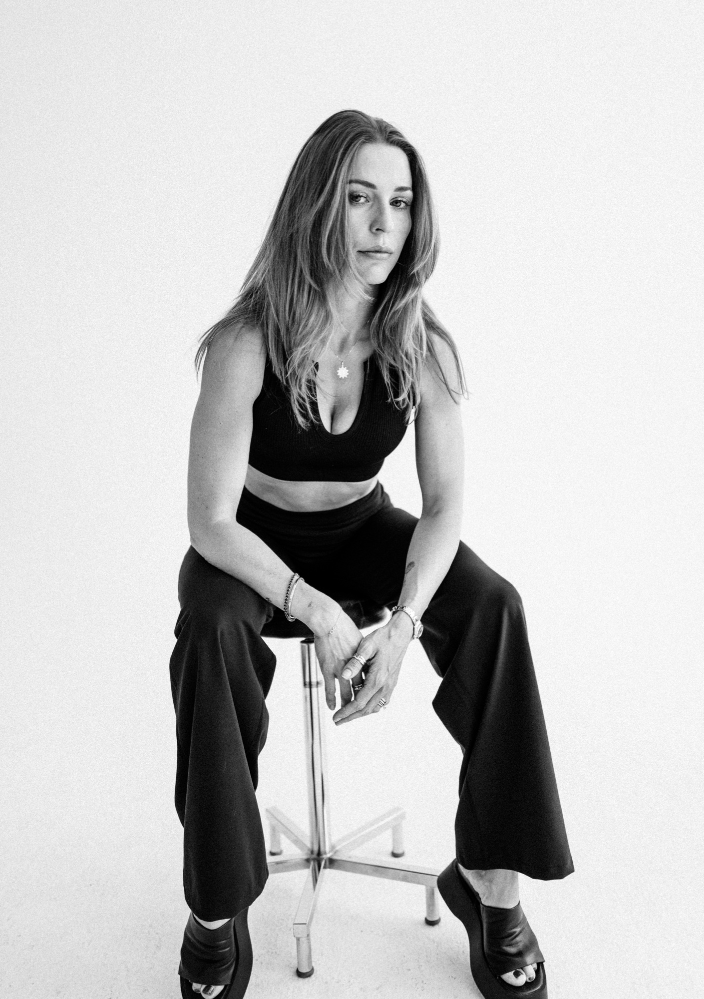 Sitzendes Model im schwarzen Crop-Top und weiter Hose mit Blick zur Kamera