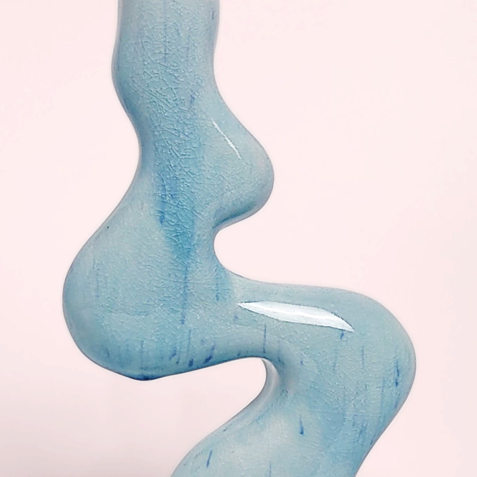Unique handmade sculptural ceramic candle holder featuring a flowing wavy form and glossy blue glaze, designed for a single tall candle