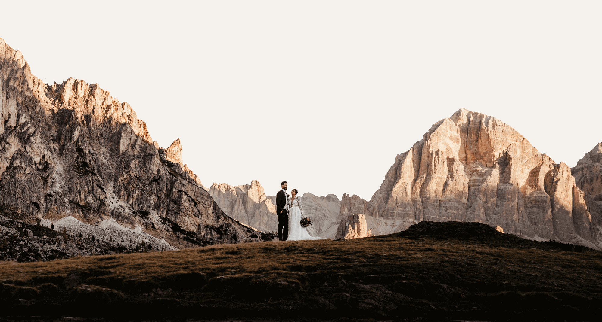 Bride and groom holding hands in front of sunlit Dolomites — emotional and wild mountain wedding photography