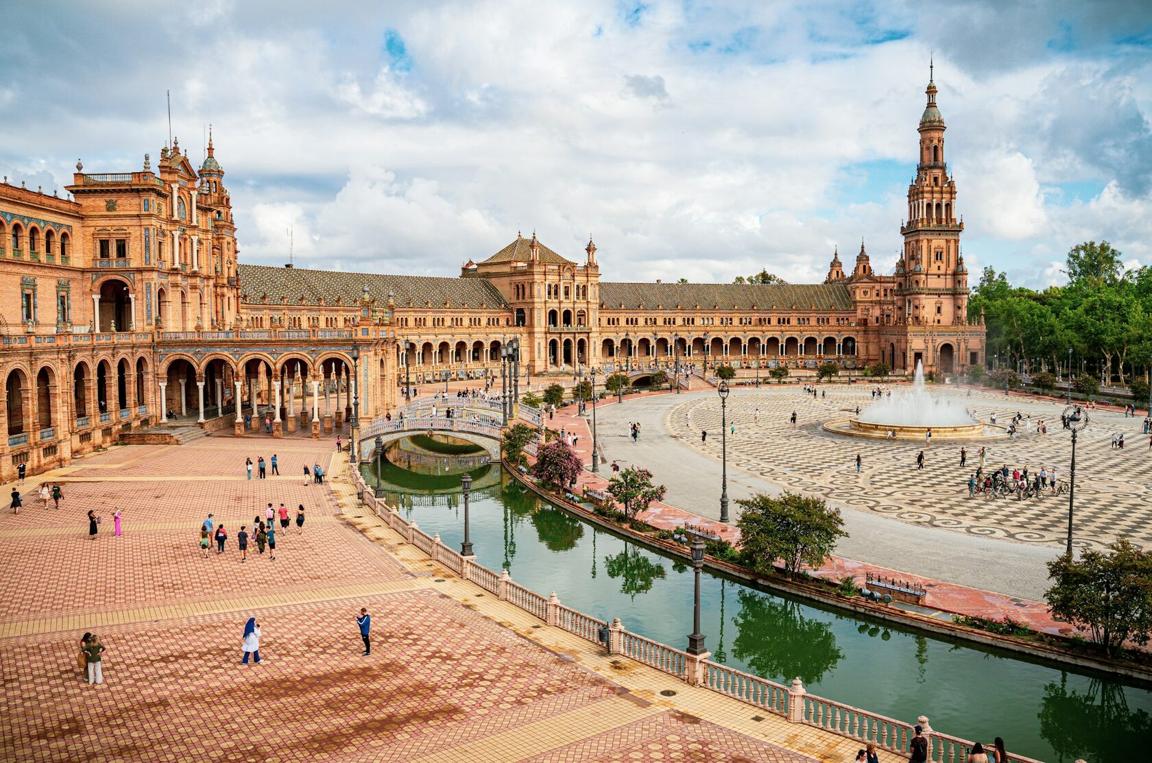 A group of travelers with their guide in Seville's Plaza de España on a bright sunny day