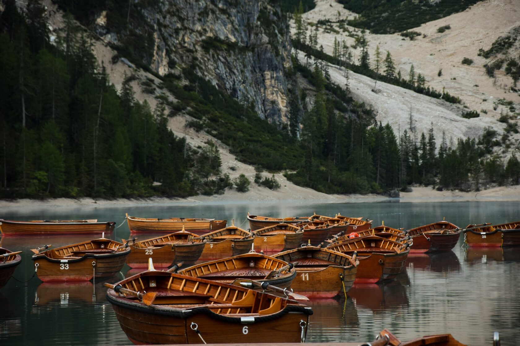 A wooden rowboat on the emerald water of Lago di Braies in the Dolomites, mountains reflected behind