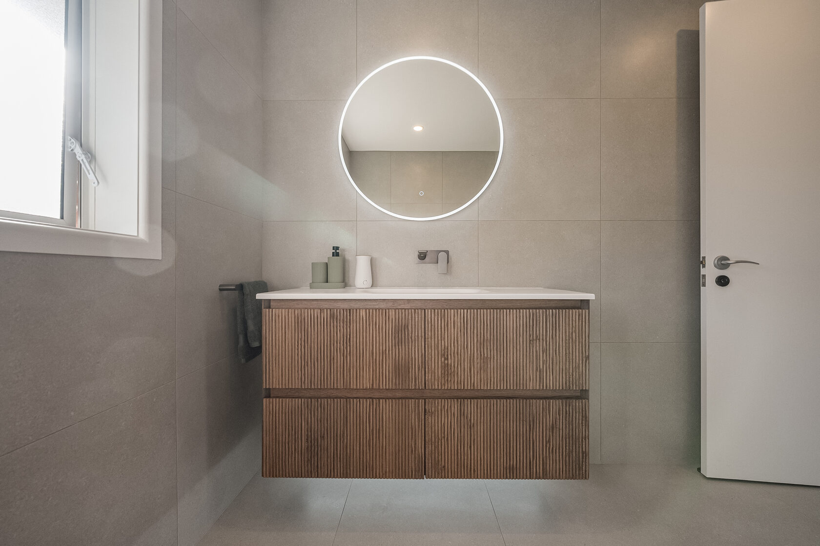 Floating timber vanity and illuminated round mirror in the Glenfield family bathroom