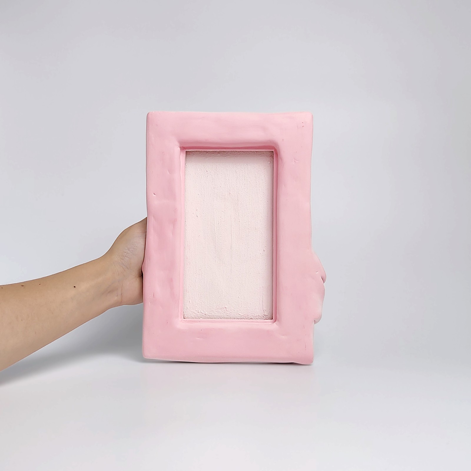 textured wall art made of air-dry clay in a soft pink shade with flowing sculpted drapery