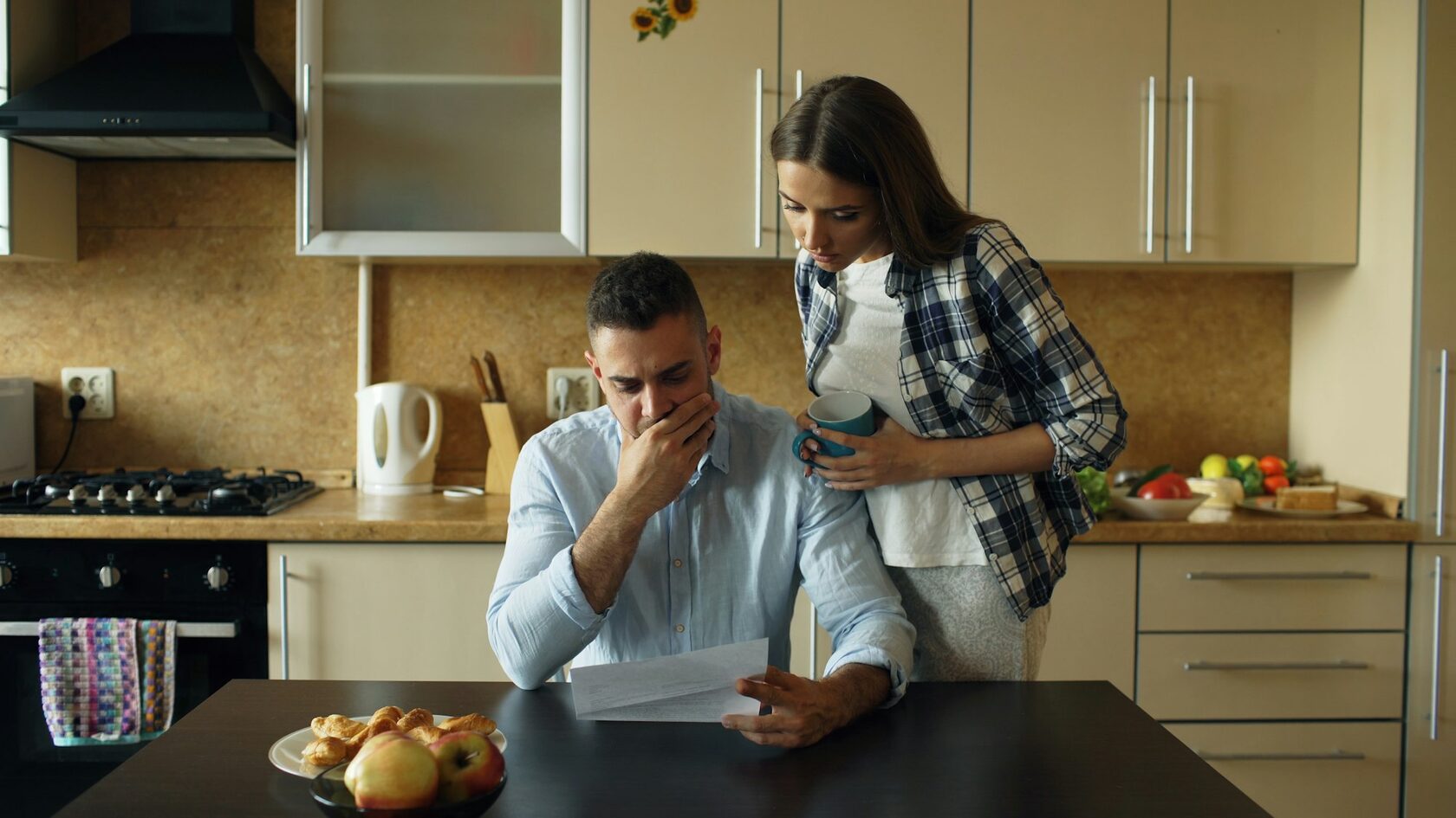 Worried couple reviewing financial debt bills with genuine stress