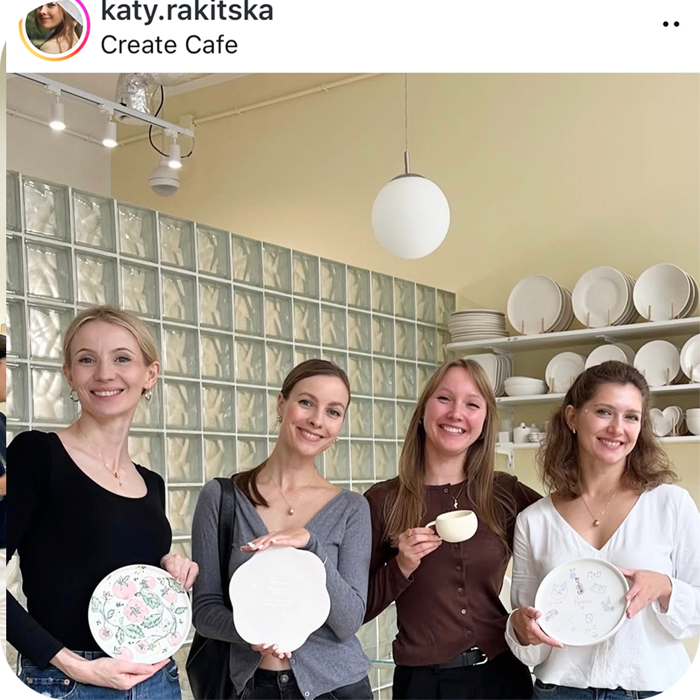 A team holding painted ceramic plates — a keepsake from a team event at Create Cafe
