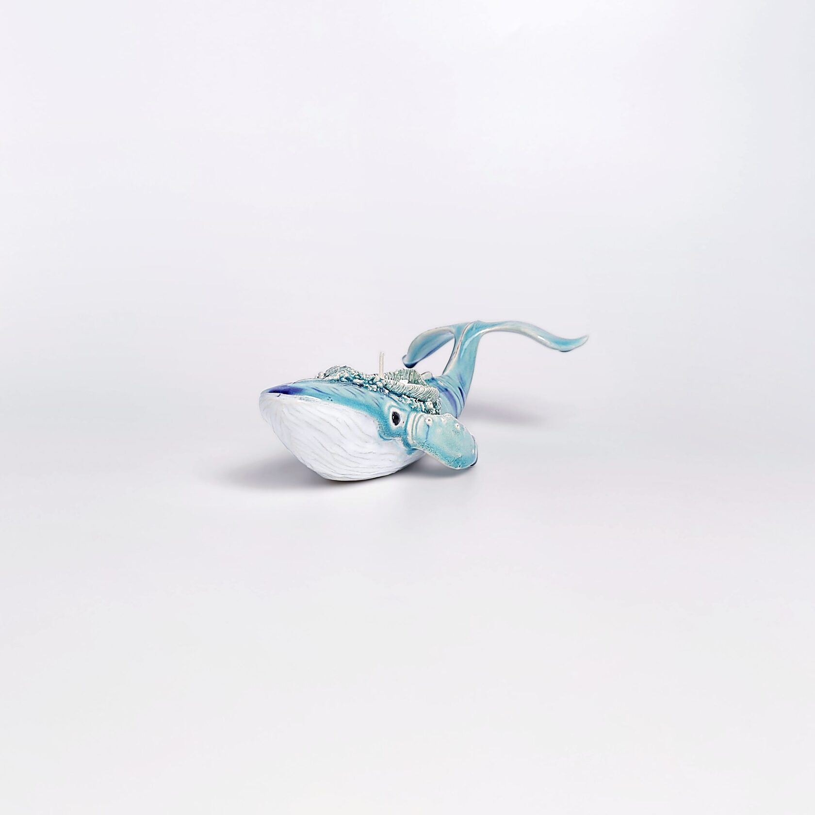 Unique handmade ceramic whale candle holder with ocean-blue glaze, detailed sculptural texture, and a built-in candle