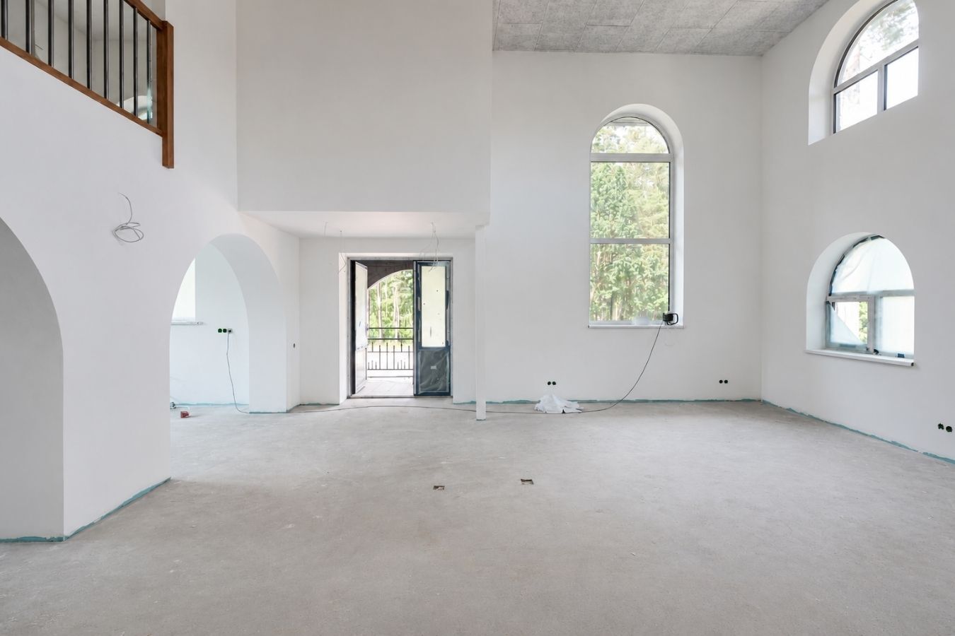 Current unfinished double-height interior with arched openings and tall windows