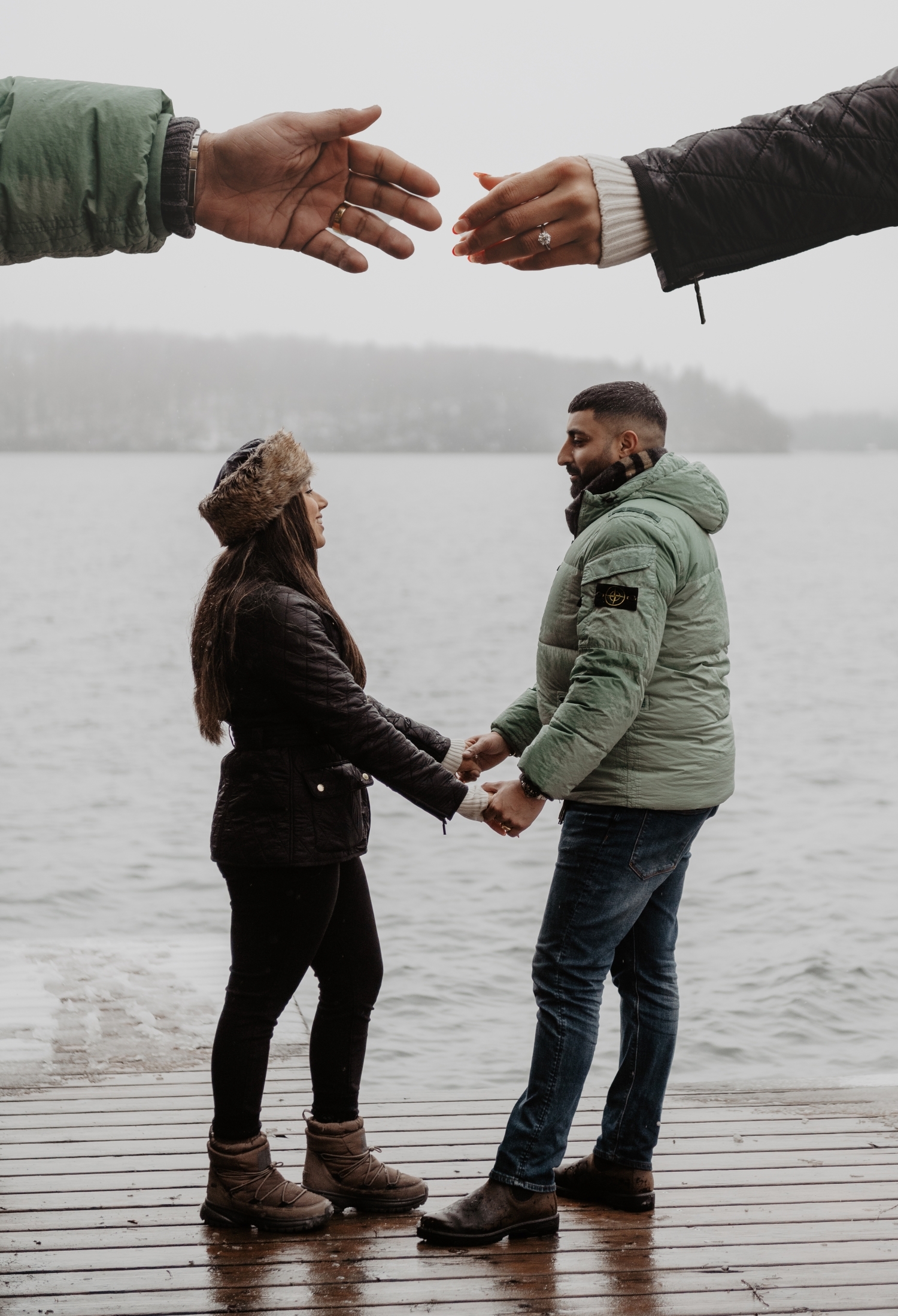 Engaged couple holding hands on a lakeside boardwalk in Austria, romantic winter couple photos