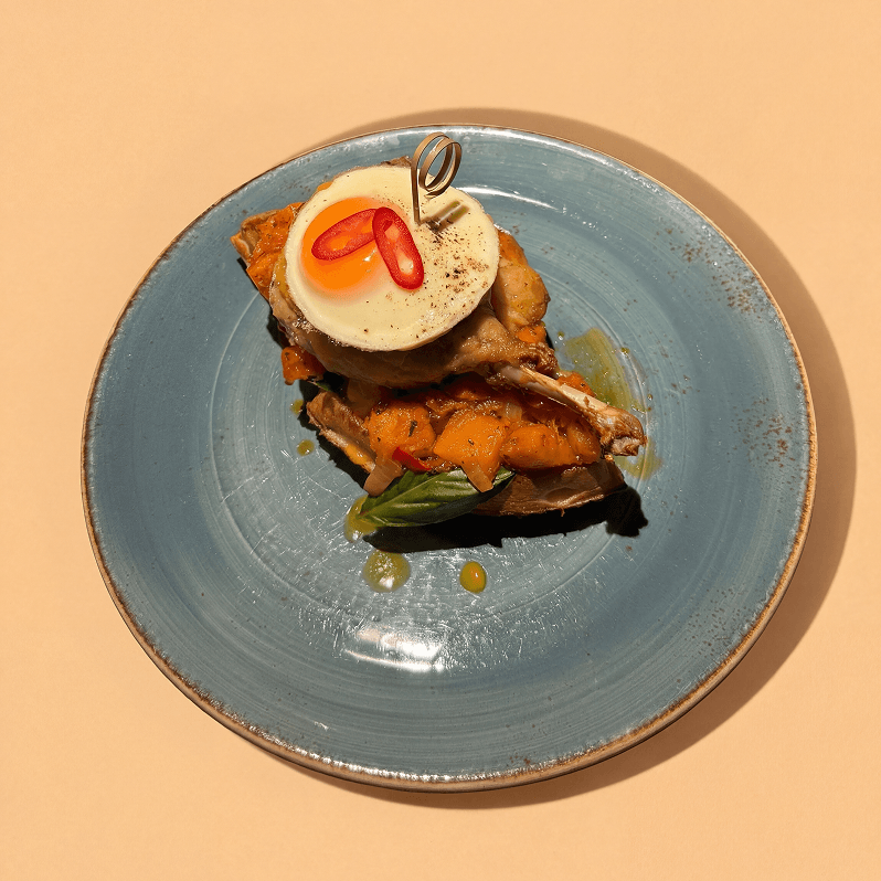 Waffle with duck leg, fried egg, pumpkin and orange sauce