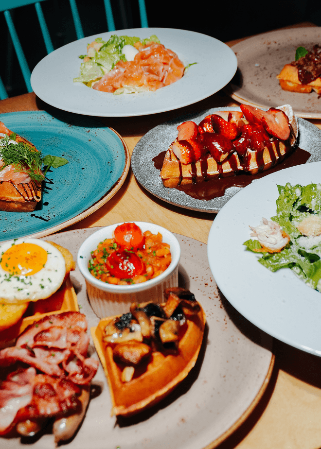 Snídaňová jídla a vafle na stole v kavárně Coffee & Waffles