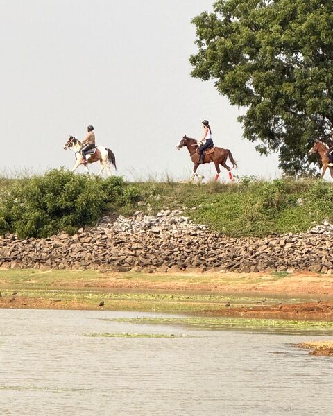 Two riders along the tank bund above the water at Punanai.