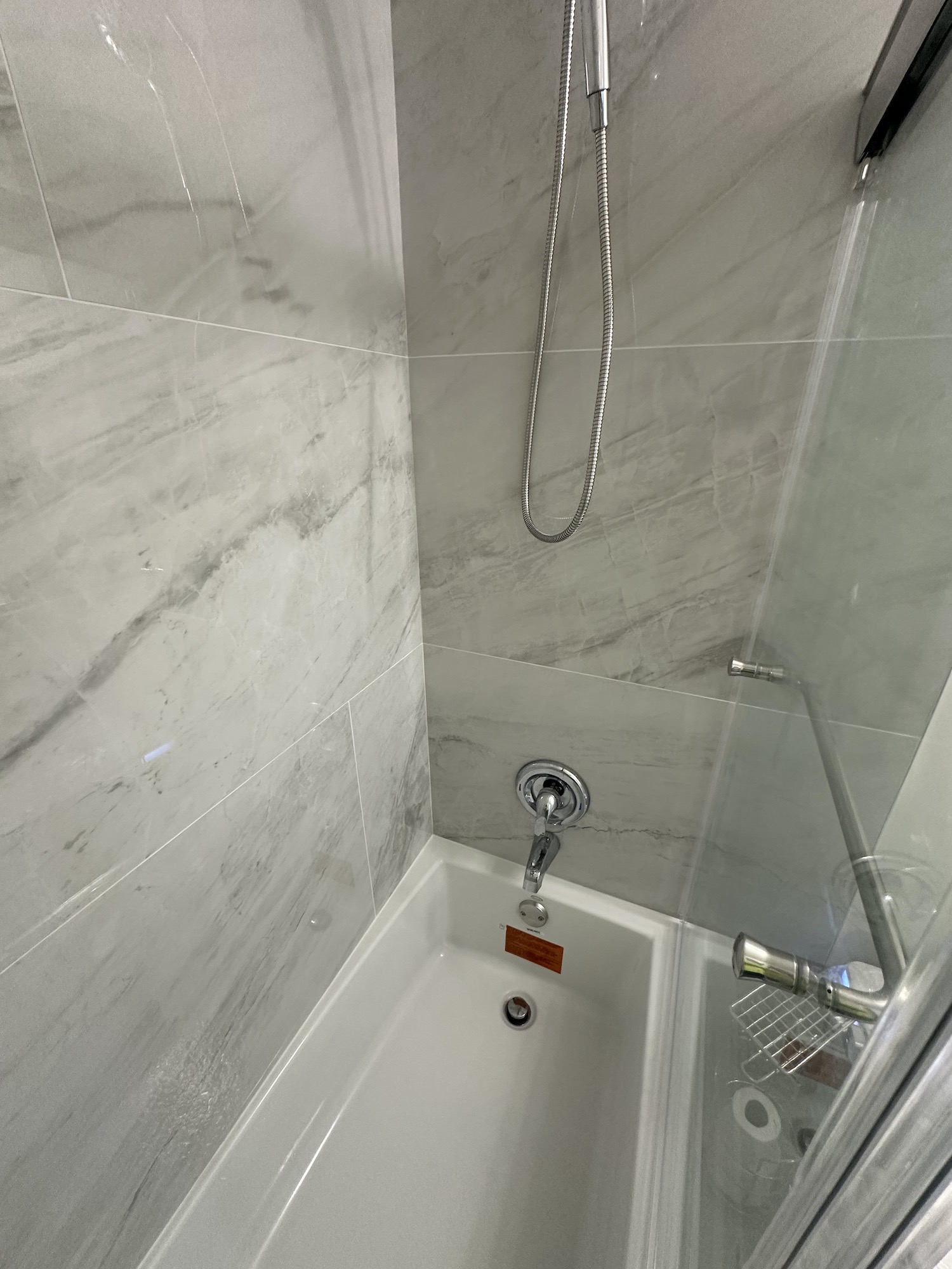 Finished large-format bathroom tile with showerhead, handheld shower and tub spout