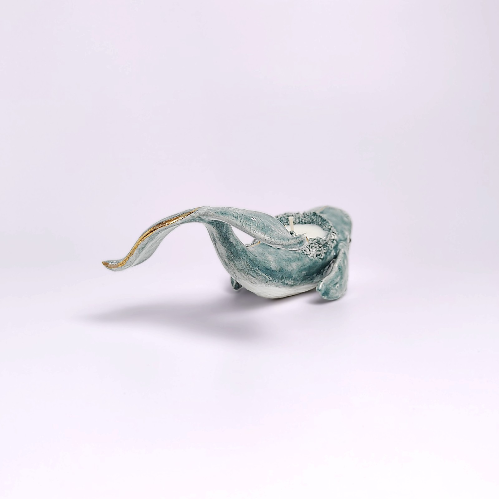 Unique handmade lagoon-colored ceramic whale with detailed sculptural texture and a built-in candle, inspired by ocean forms