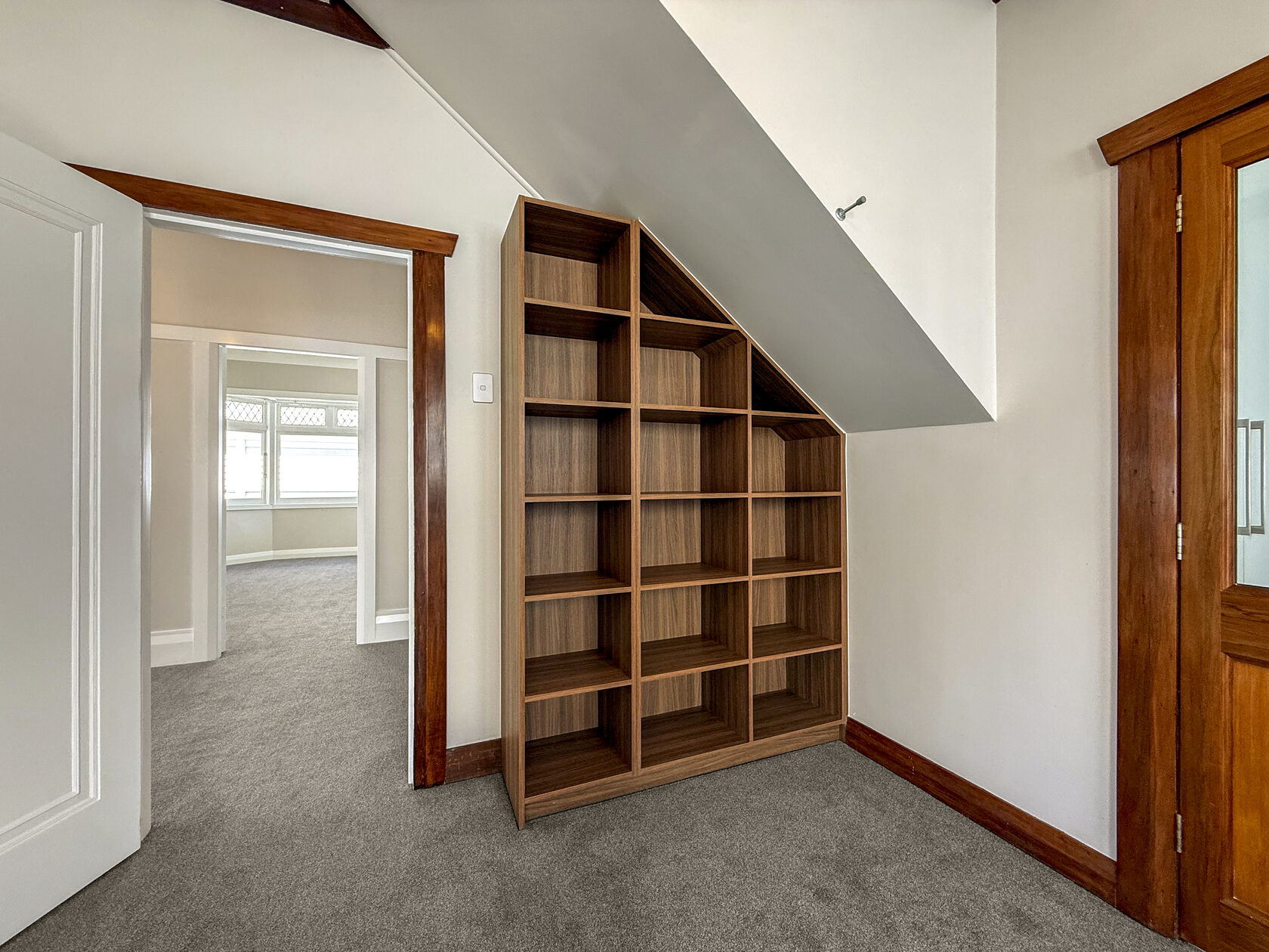 Timber shelving fitted beneath the staircase beside an original timber door