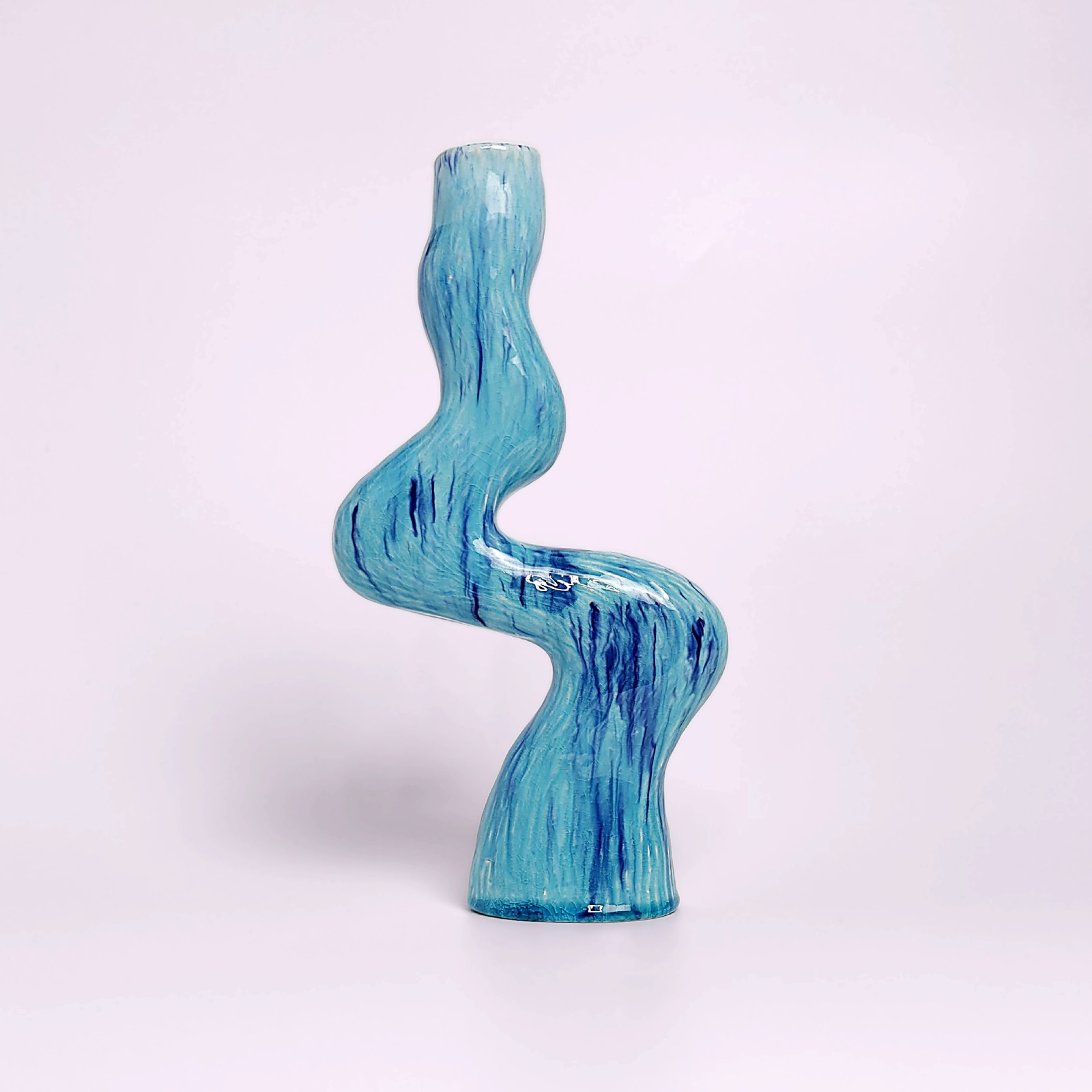unique handmade ceramic candle holder for a single candle, featuring an organic wavy shape and blue glaze with watercolor-like drips
