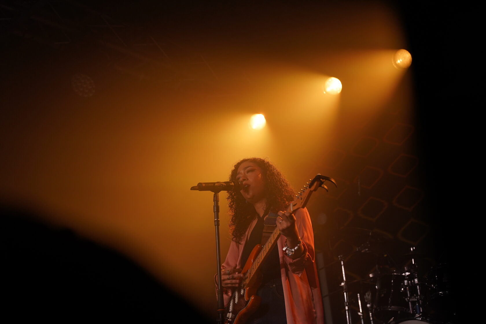 A live singer performing beneath warm amber stage lights