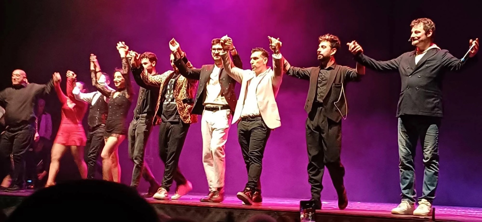 Gli artisti del galà La Magia per un Sorriso si tengono per mano e salutano il pubblico sul palco
