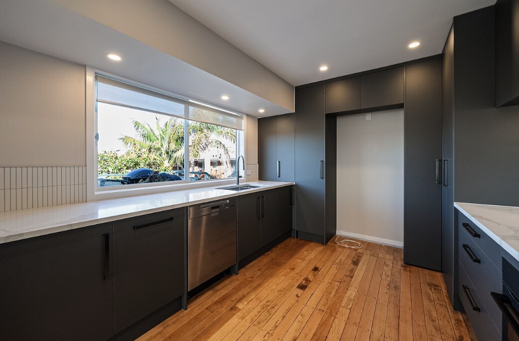 After: renovated Glenfield kitchen with dark cabinetry and restored timber floor