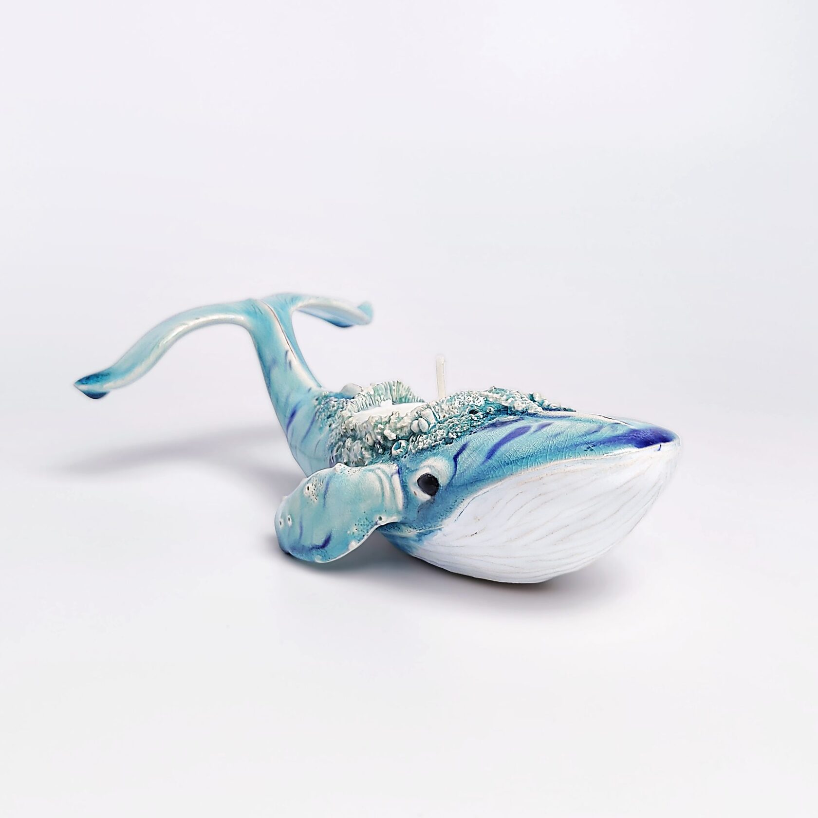 Unique handmade ceramic whale candle holder with ocean-blue glaze, detailed sculptural texture, and a built-in candle